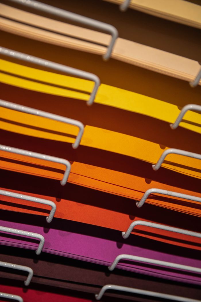Vertical shot of a colorful paper rack organized by color, ideal for stationery enthusiasts.